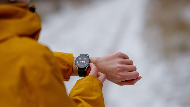 Person using side buttons on a smartwatch fitness tracker on their wrist.