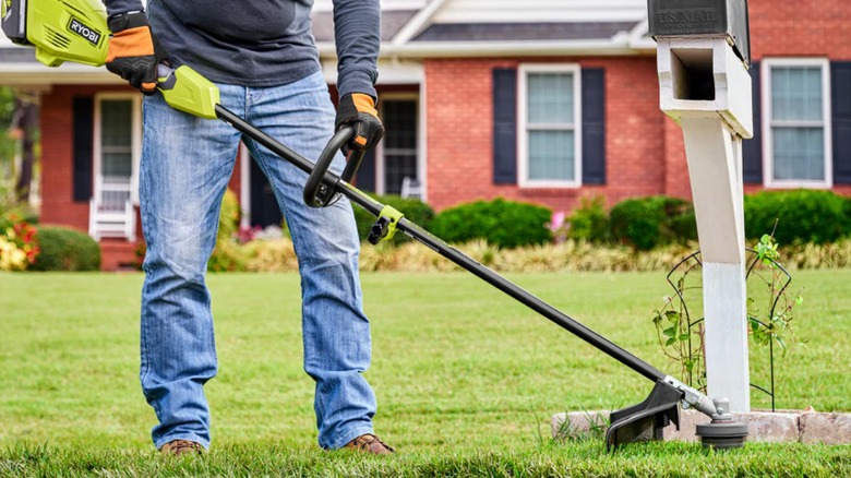 Landscaper cutting around mailbox with Ryobi string trimmer