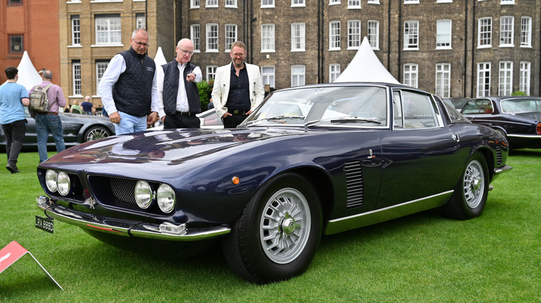 A dark blue Iso Grifo GL350 from the 1966 model year displayed at an event outside an old building.