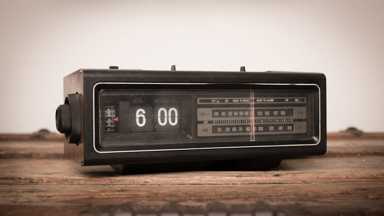 An old black digital clock radio sitting on a wood surface