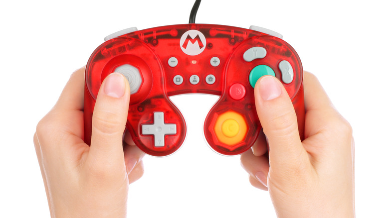 pair of hands holding Mario-style gamecube controller