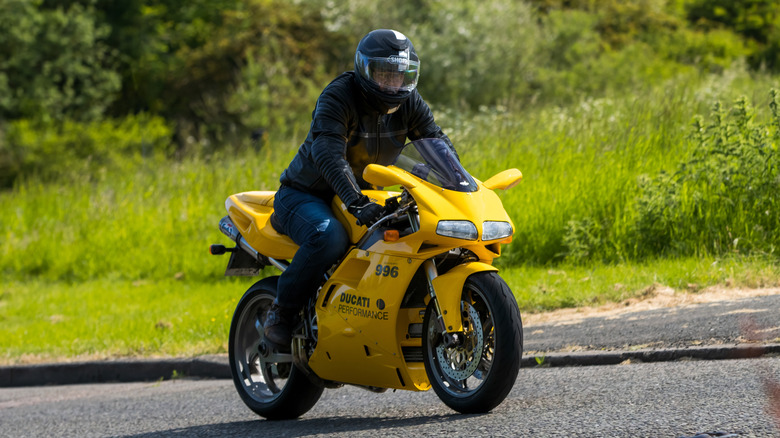 2001 yellow DUCATI 996 BIPOSTO classic motorcycle travelling on an English country road.