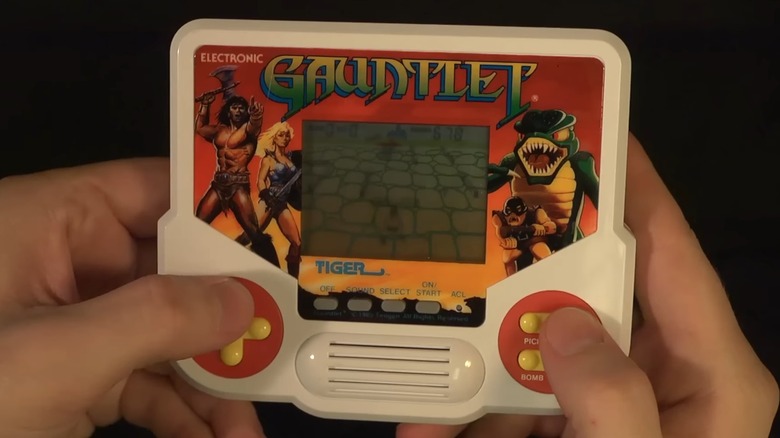 Two hands holding and playing the Tiger Electronics Gauntlet handheld game