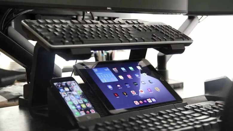 A device stand holding a keyboard, an iPad, and an iPhone.