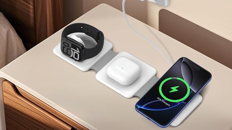 A charging station on a bedside table charging an Apple Watch, AirPods, and an iPhone