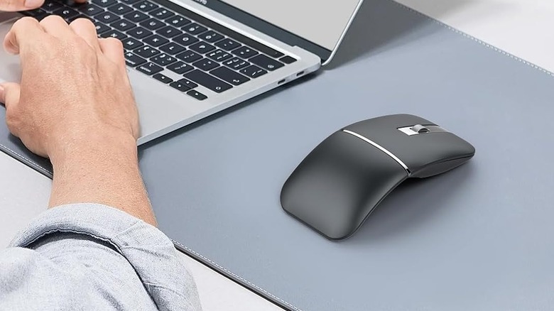 A person using a laptop with a foldable mouse next to them