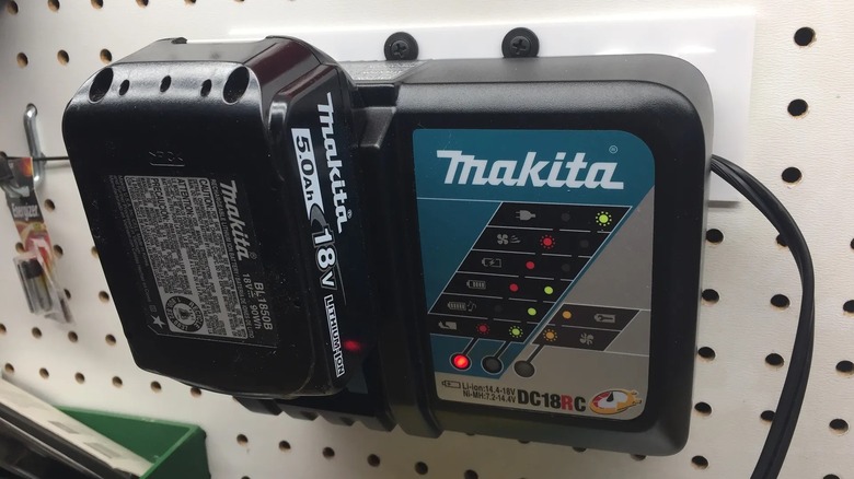 A Makita 18 volt battery hung on a pegboard.
