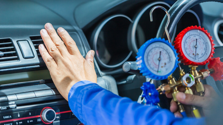 technician holds a monitor tool to diagnose the car's AC system