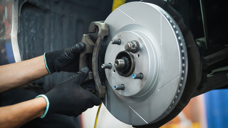 auto mechanic replacing front wheel brake pads and calipers