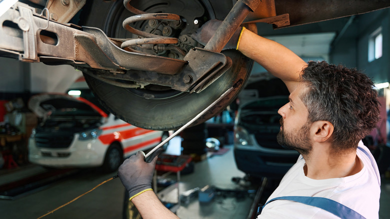 auto mechanic  working on a vehicle's rear suspension