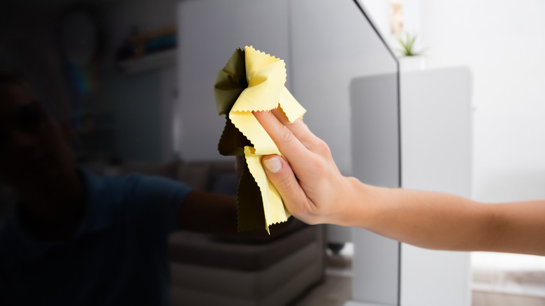 Close up of using cloth to clean TV
