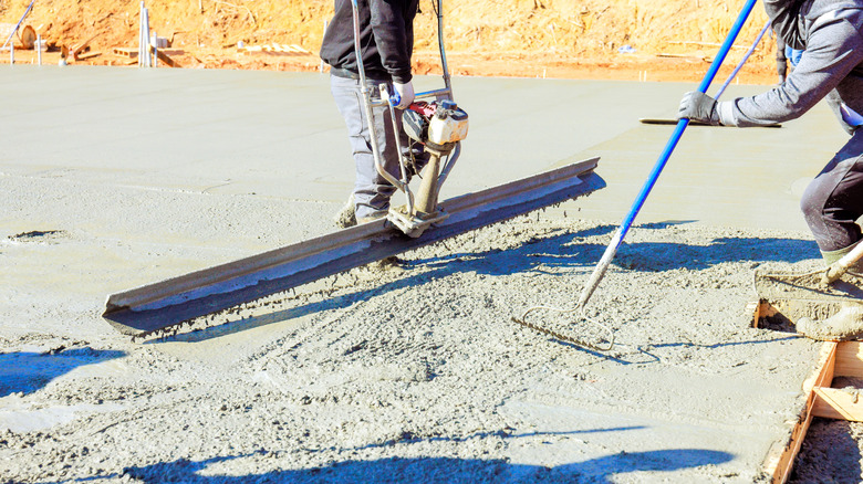 Workers smooth laid concrete.