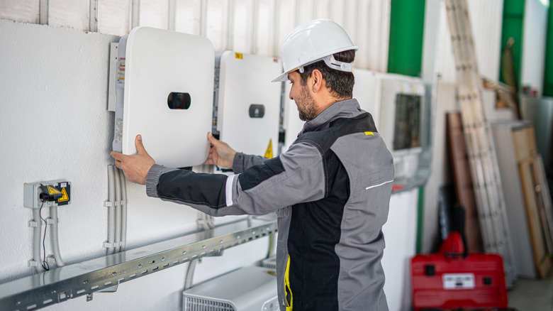 A worker placing a cover on a series of energy meters on the side of a building