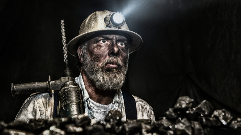 man in coal mine holding heavy duty drill