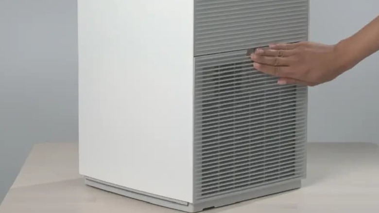 A person touching the vent on a Daikin air purifier.