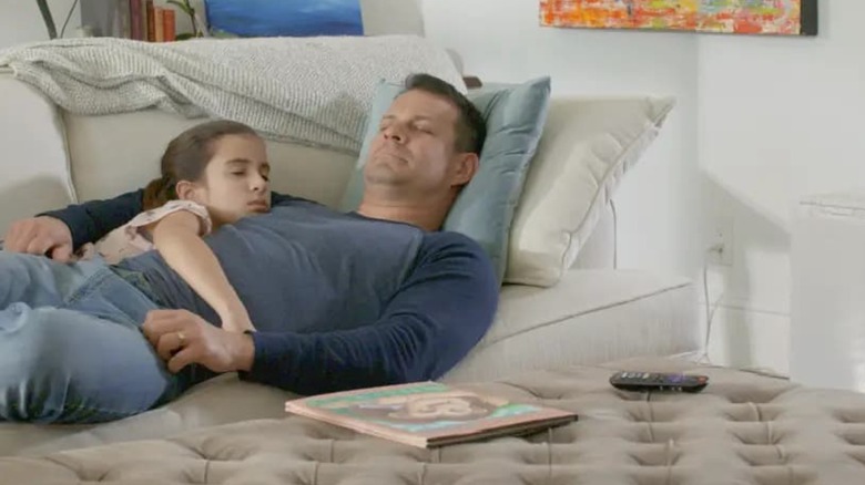A man and his daughter sleeping on a couch next to a Daikin air purifier.