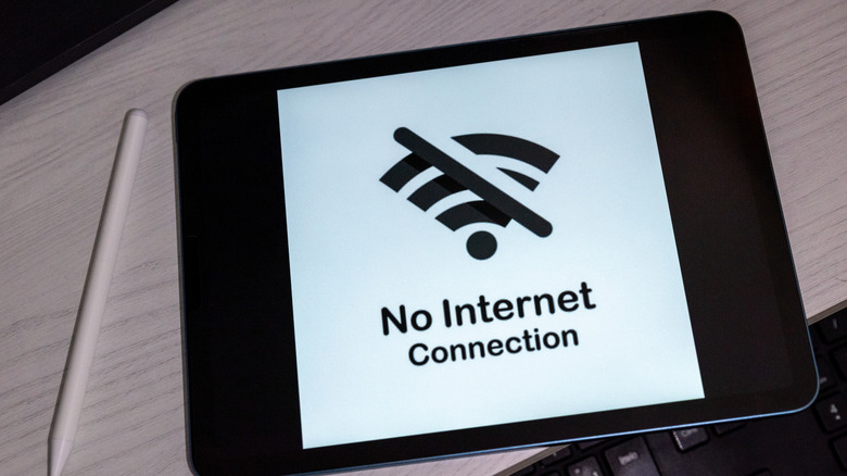A tablet with a large black and white "no internet connection" display sitting on a wooden surface