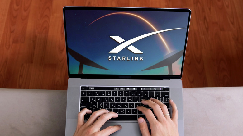 Close-up of hands on a laptop displaying the Starlink website