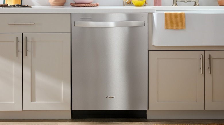 Whirlpool dishwasher flanked by beige cabinetry