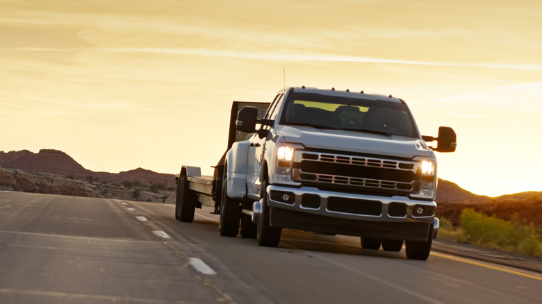 Pickup truck driving down highway pulling trailer