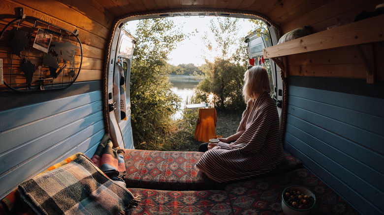 woman inside back of van looking into beautiful lake