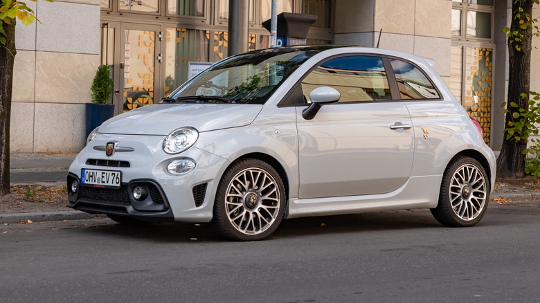 A light gray Abarth 500 parked on a city street, front 3/4 view
