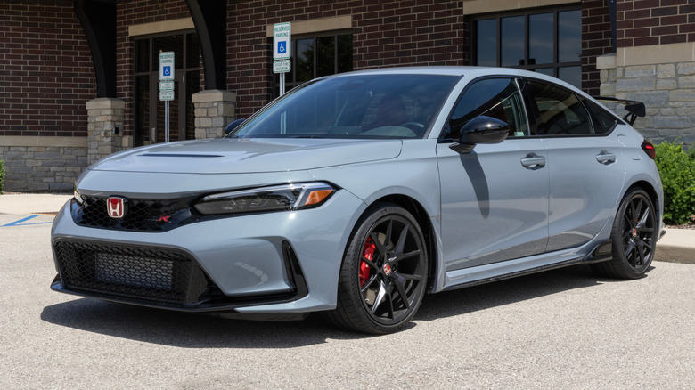 A gray Honda Civic Type R parked in front of a building.