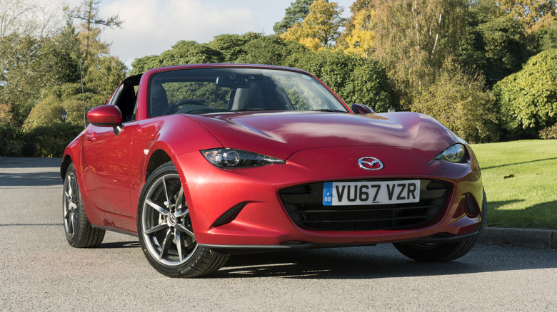 A 2017 red Mazda MX-5 parked in the middle of the road.