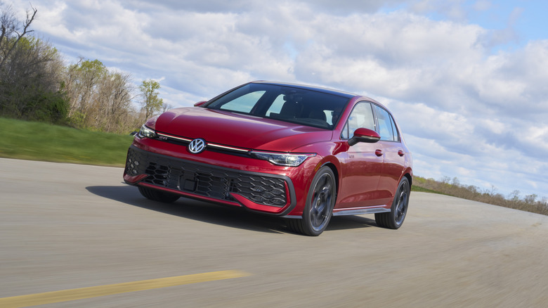 A red 2026 VW Golf GTI on the move, front 3/4 view