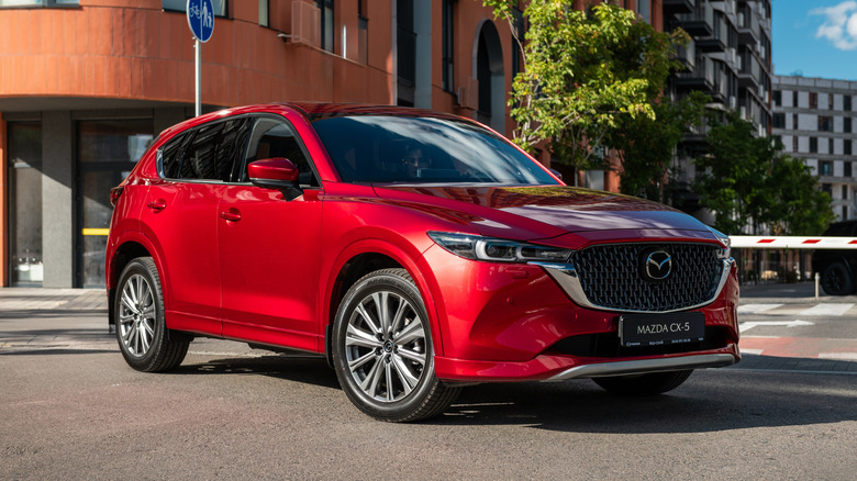 A red Mazda CX-5 parked in front of a residential building.