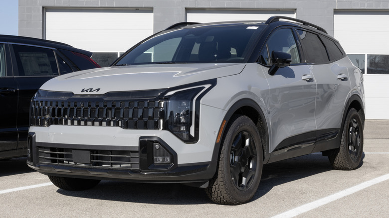 A gray 2026 Kia Sportage SUV parked in front of an industrial building.
