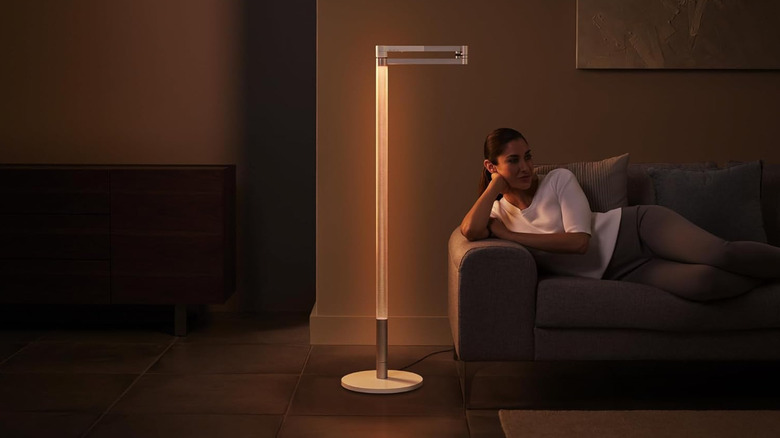 A person lounging on a couch next to a Dyson Solarcycle Morph floor light