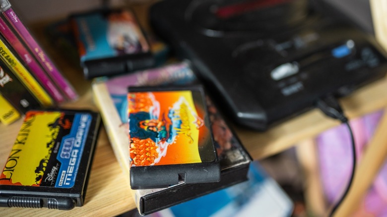 Shallow-focus photo of a Sega Genesis and game cartridges on a shelf
