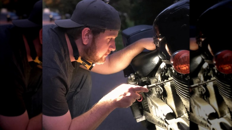 man using neck lamp while repairing motorcycle
