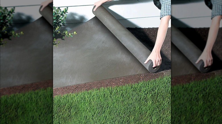 person rolling fabric on grass