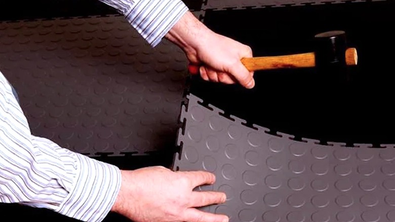 Person installing floor tiles with a hammer