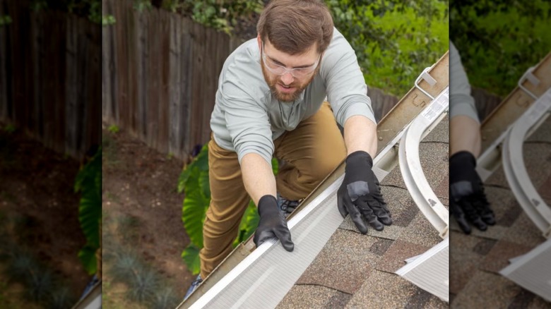 A man installing gutter guard on a roof