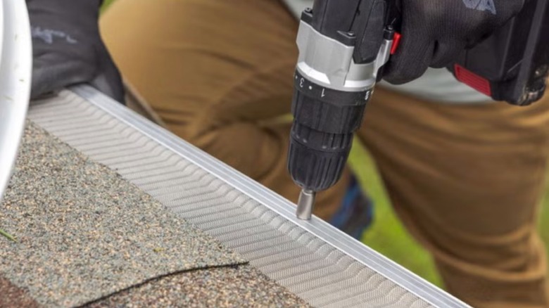 A gutter guard being installed by a man