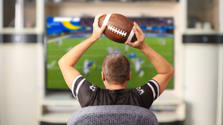 Man holding football and watching football
