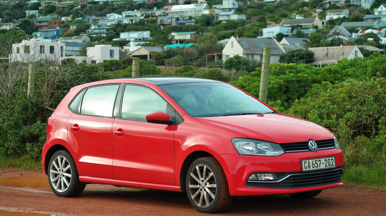 A red Volkswagen Polo on an untarred road in South Africa.