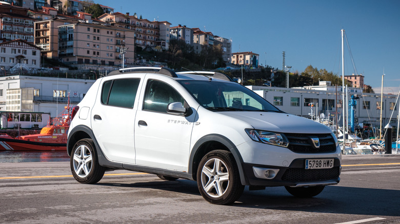 A white Dacia Sandero parked by a river in Spain.