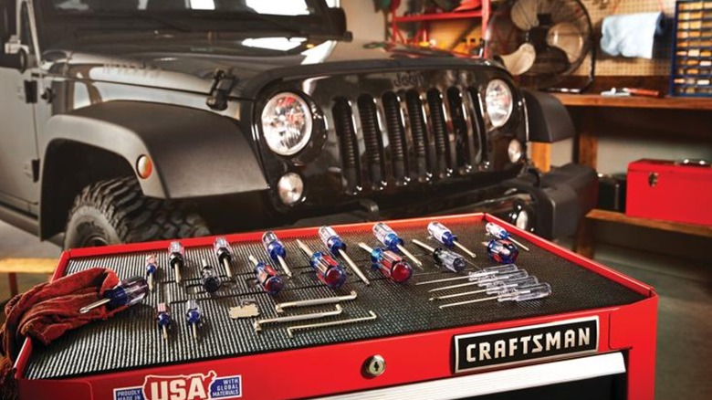 Tools placed on top of toolbox with jeep in background