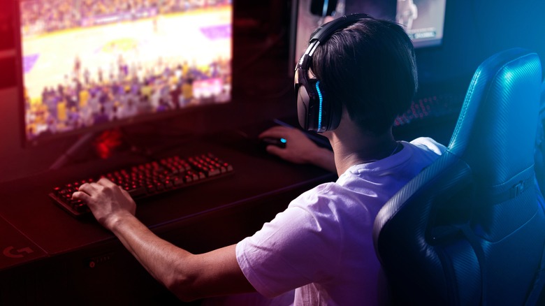 Guy wearing headphones, sitting at his computer and playing video games