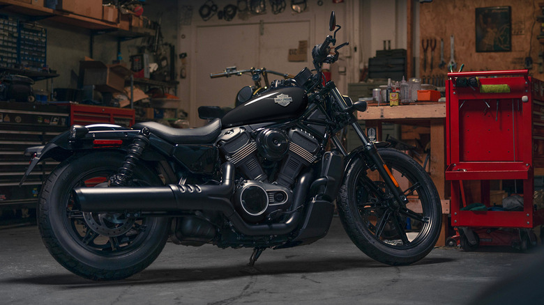 A balcked-out Harley-Davidson Nightster motorcycle parked inside a garage, bathed in warm, yellow light at night.