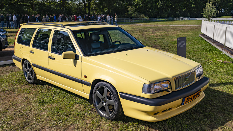 Front 3/4 view of yellow Volvo 850 wagon parked on display at car show.