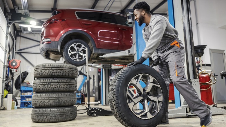 A mechanic rotating the tires on a car in an auto repair center.