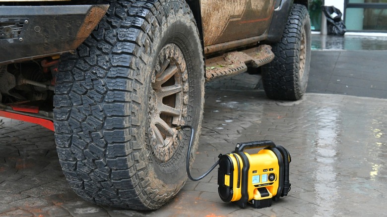 An air pump attached to a tire of a large car.