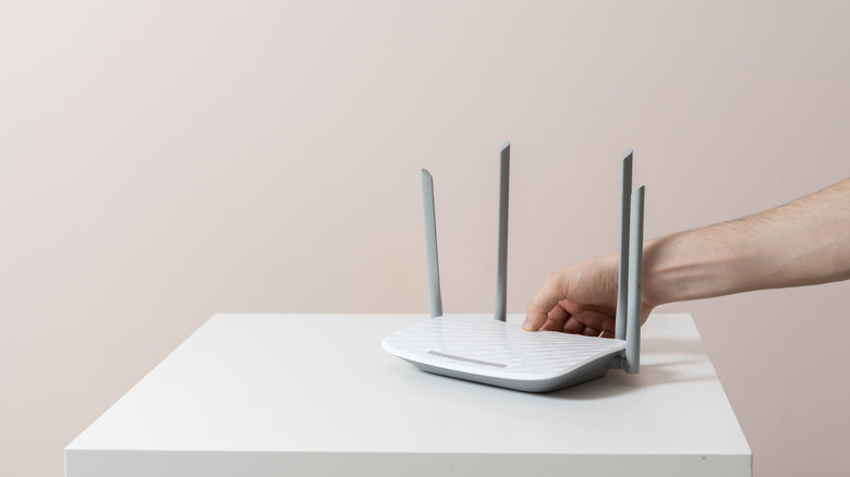 A hand setting a wifi router down on a table