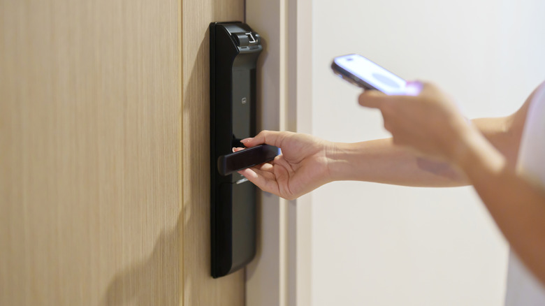 A person using a smart lock on their front door with a smartphone