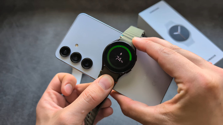 A Samsung smartwatch being charged on the back of a Samsung phone